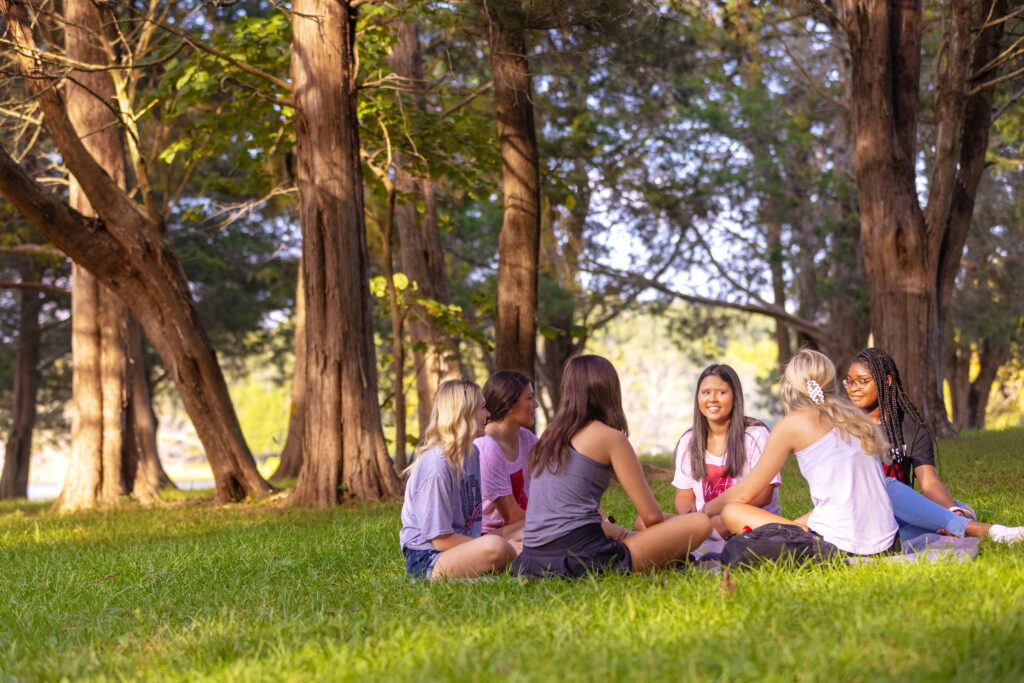 six students sitting on the campus lawn