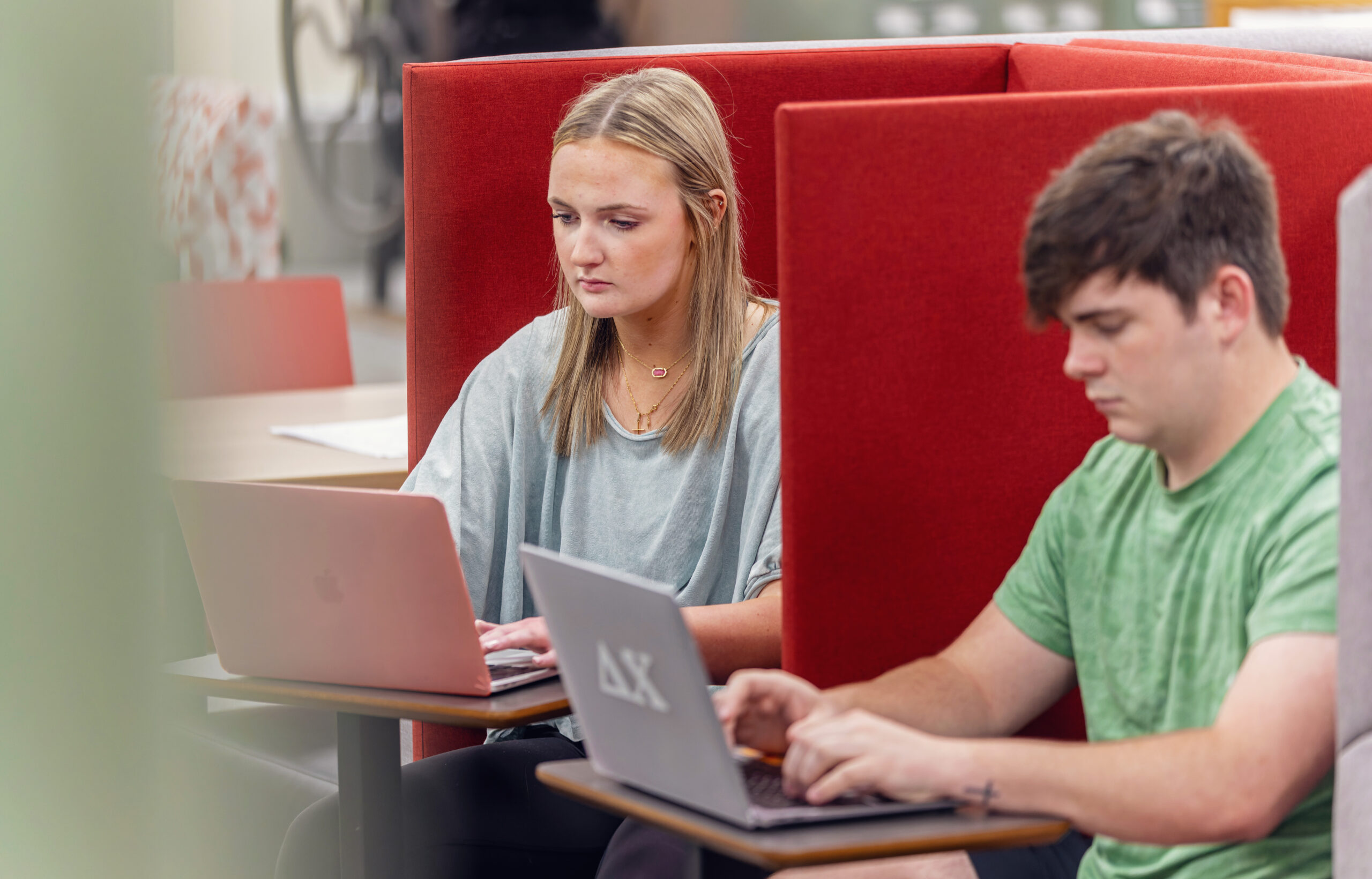 Two UWA students use their laptops in study spaces on campus