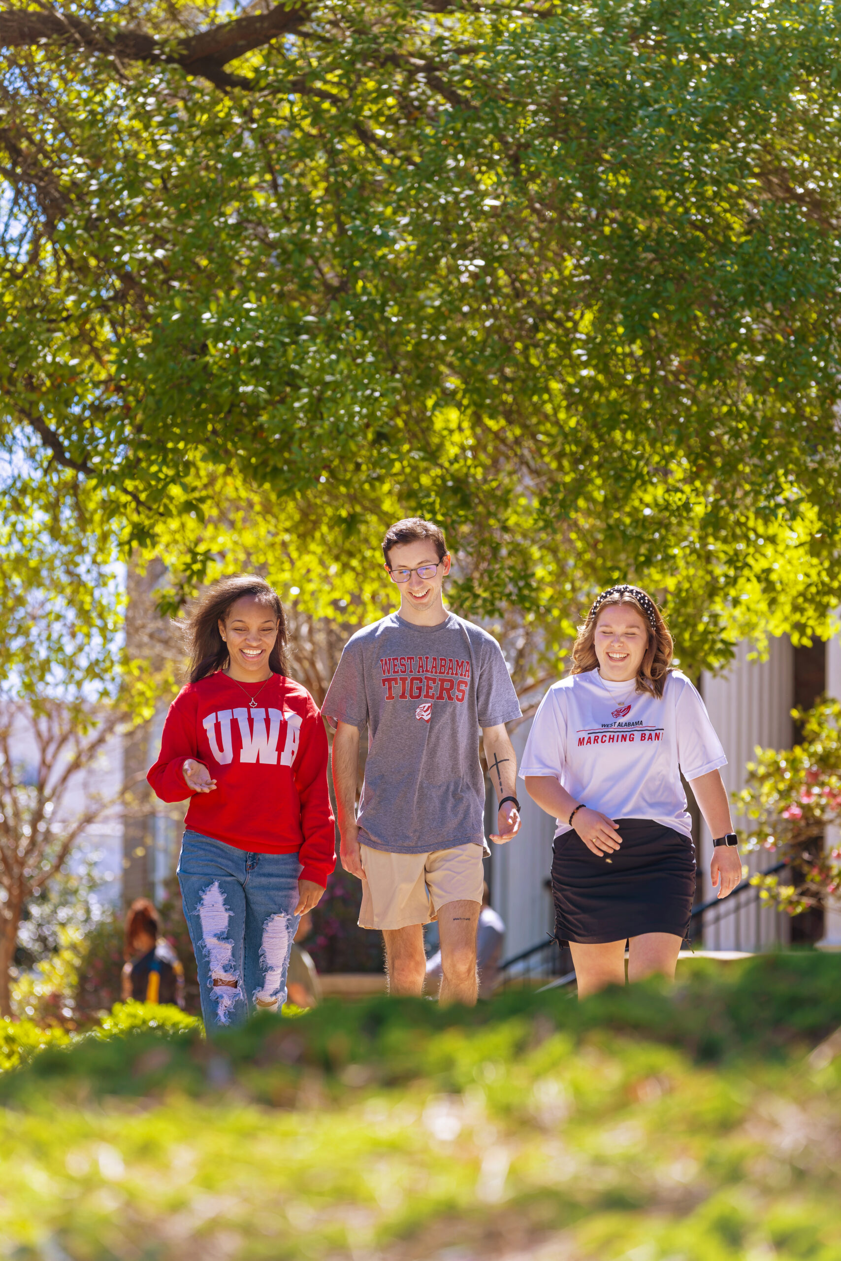 Three UWA students laughing as they walk on campus