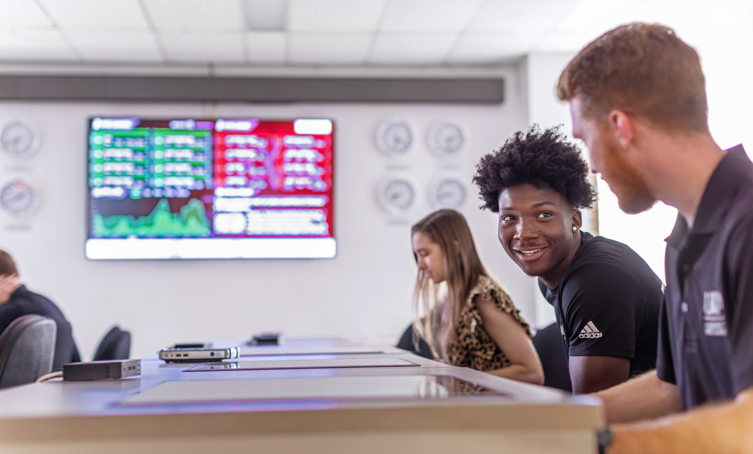 Three UWA students sit at desks with stock table in background