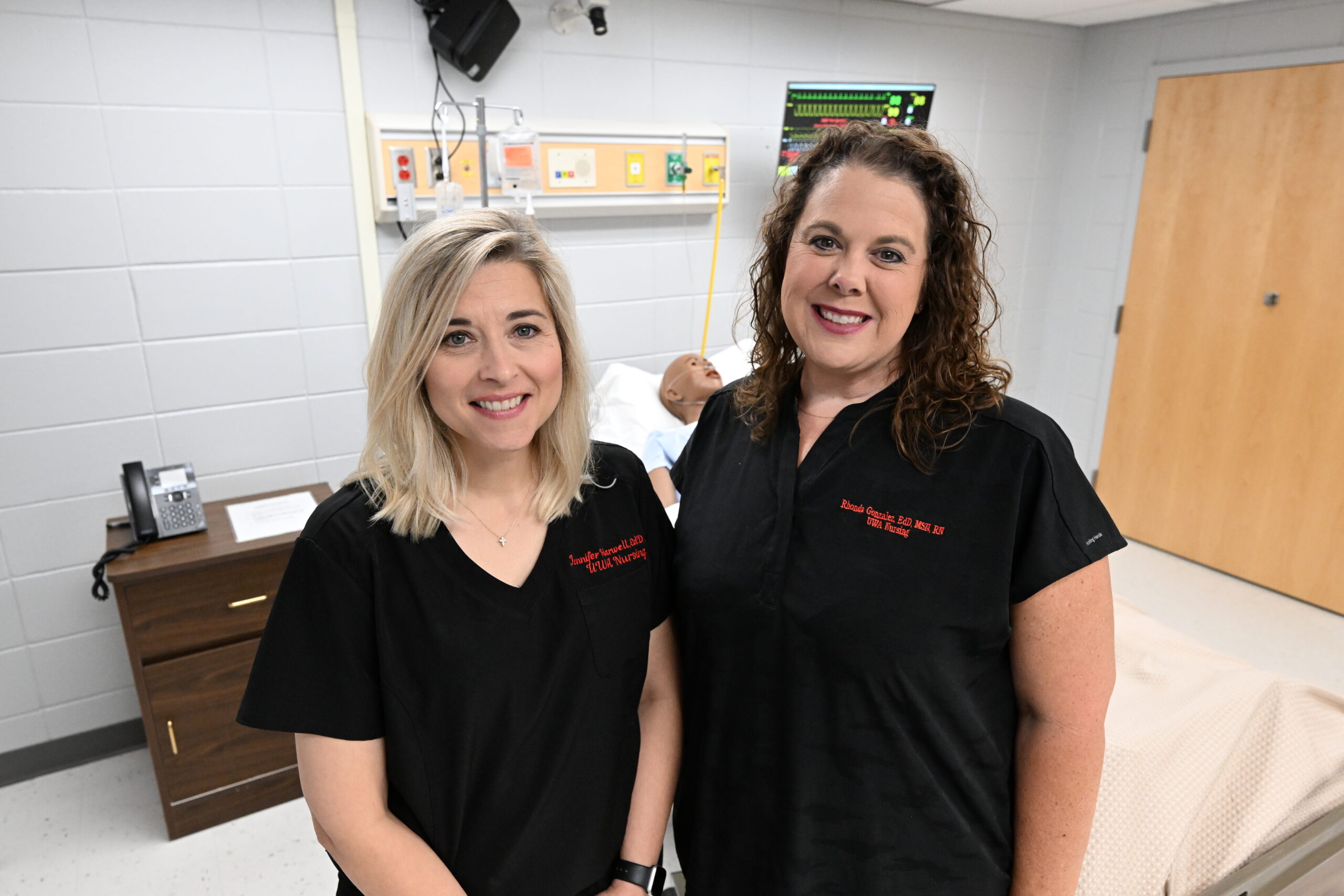 Nursing Professors Jennifer Harwell and Rhonda Gonzalez pose in a clinical simulation room